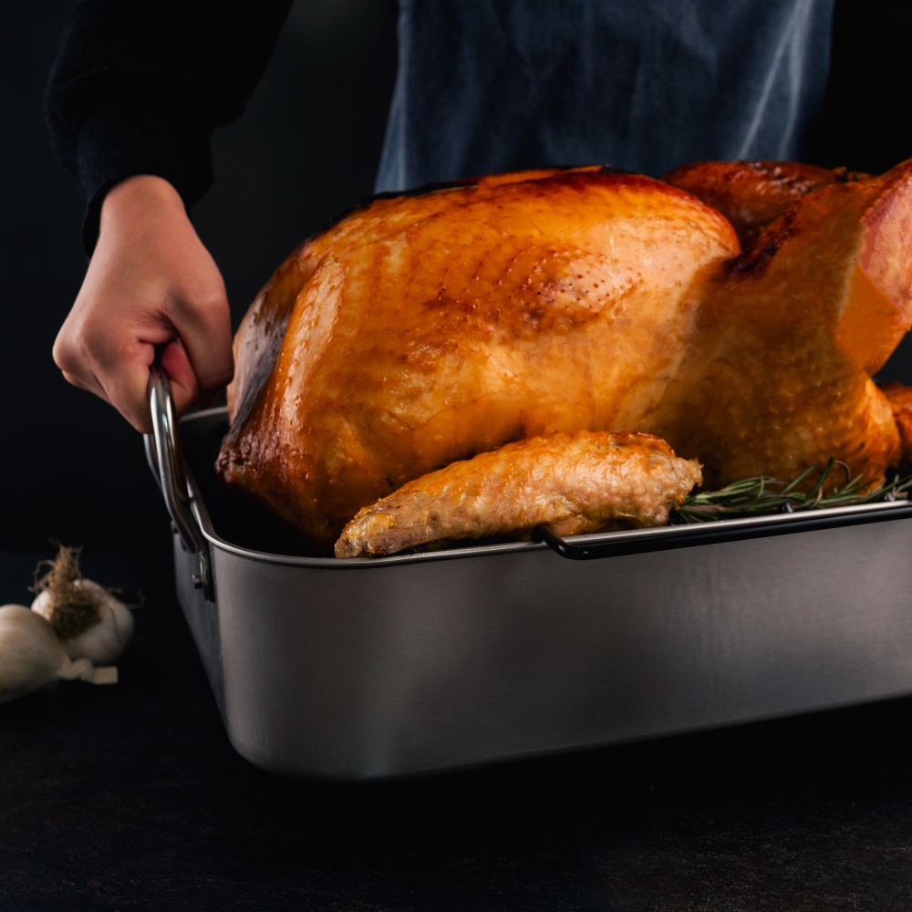 Roasted turkey in a roasting pan with a dark background