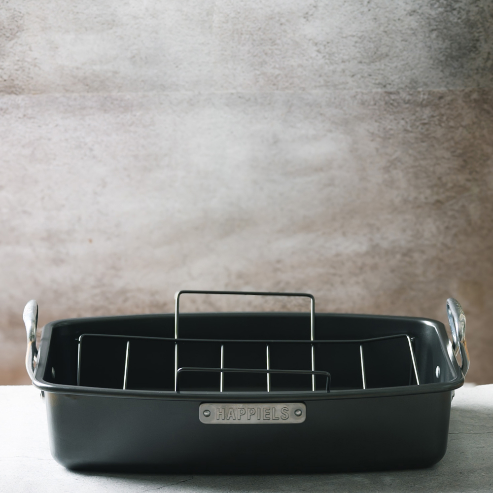 Black roasting pan with handles on a neutral background