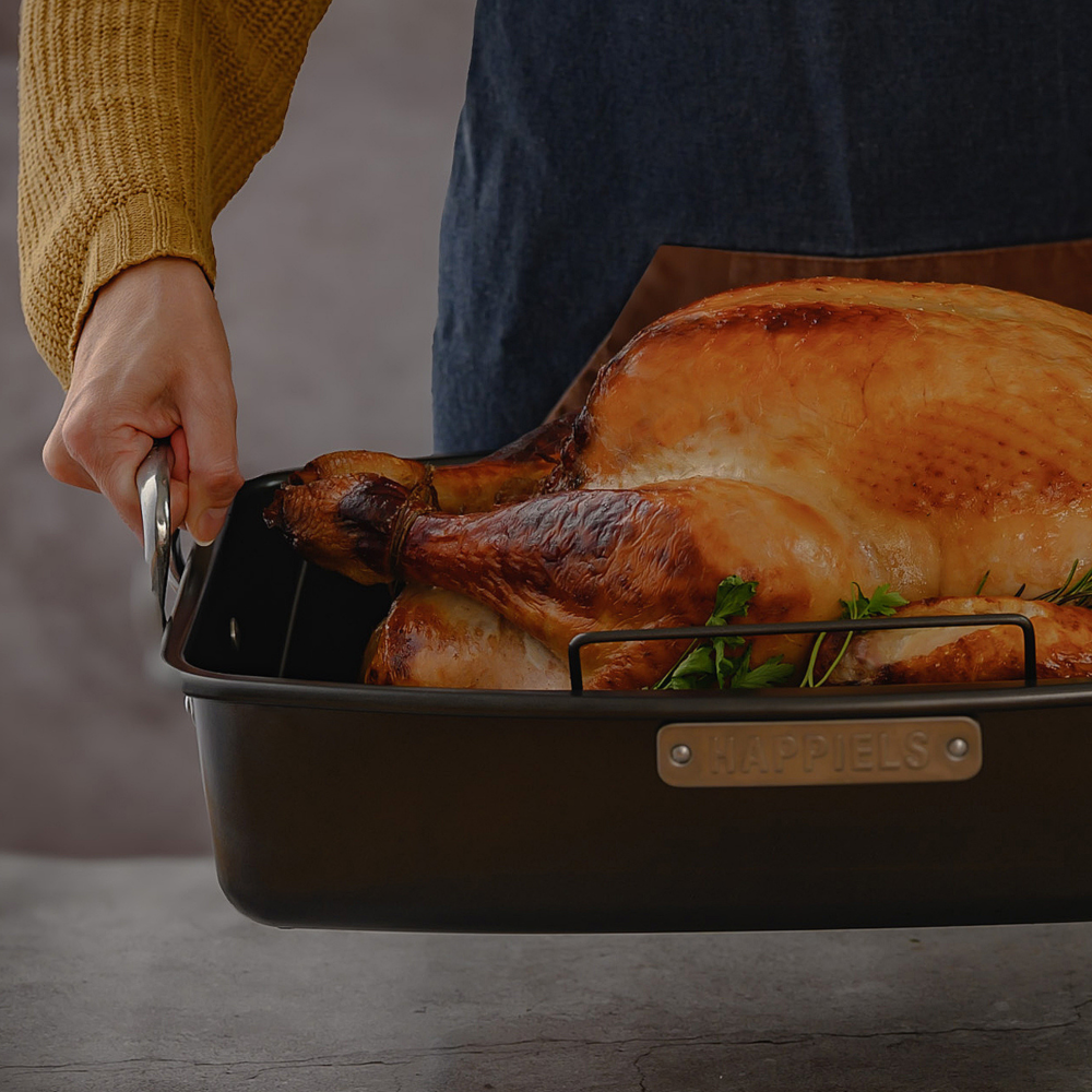 Roasted turkey in a baking dish with a person holding the handle.